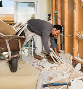 A man gathers construction junk in a bare room.