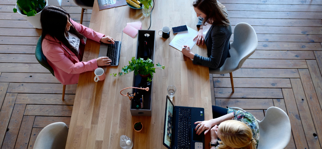 Three female colleagues sitting together in a clean co-working space.