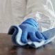 A close-up of a person's hand cleaning a table. This person is wearing a protective gear and glove.