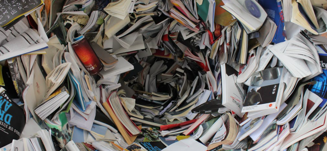 A swirling vortex of colorful books and papers. Text on some book spines is visible.