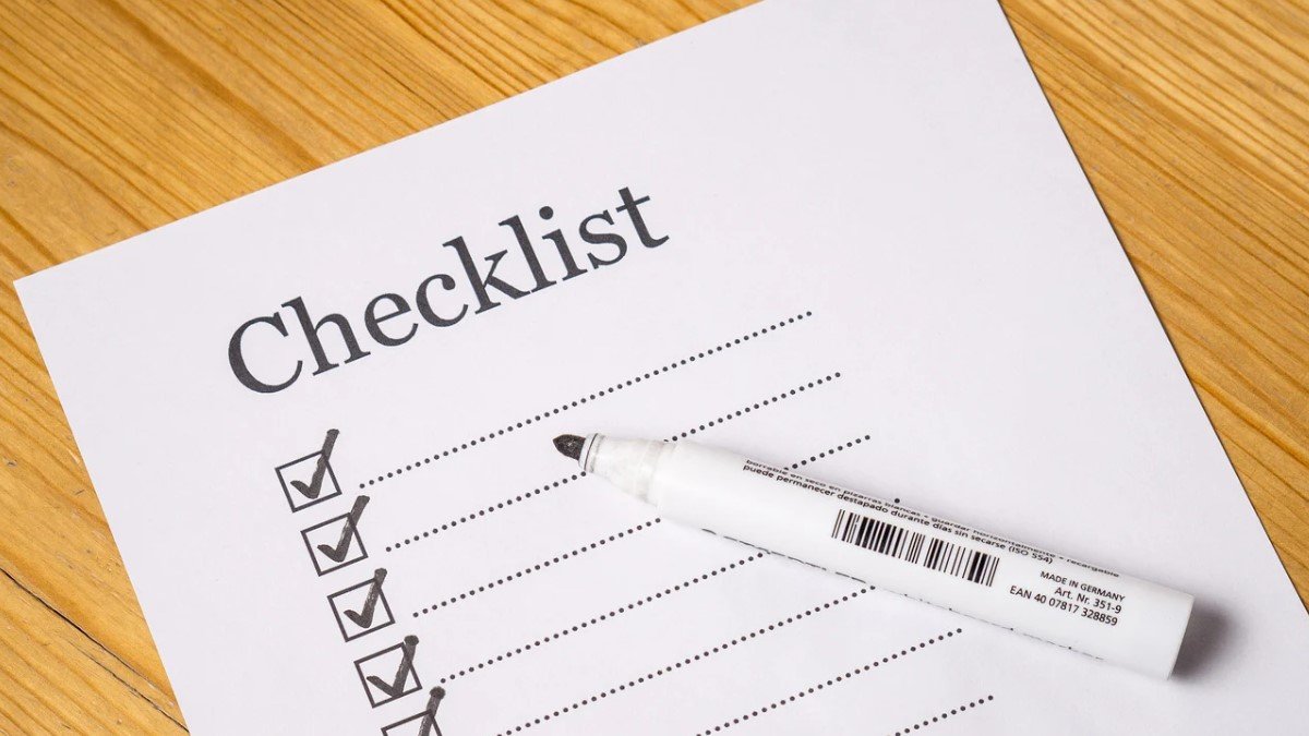 A checklist with checkmarks and a white marker on a wooden table, implying the importance of regular AC maintenance to ensure optimal performance and energy efficiency.