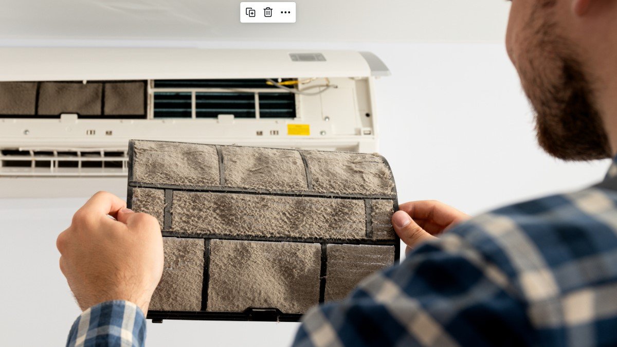 A male contractor takes out a dusty filter from an AC unit.