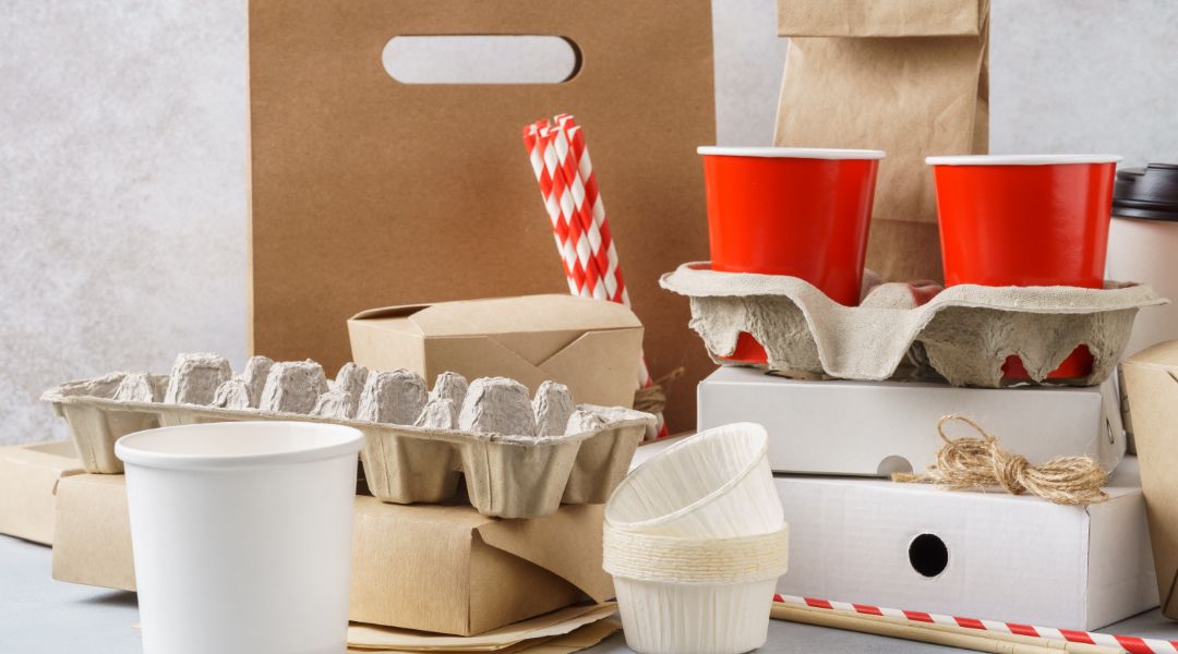 A collection of paper food packaging items, including paper bags, cups, straws, and containers.