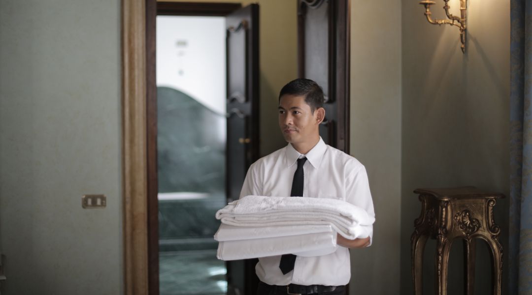 Hotel staff member delivering freshly laundered linens to a guest room, ensuring top-quality service and comfort for hotel guests.