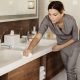 Hotel cleaning staff using eco-friendly cleaning products to wipe down a bathroom counter, promoting sustainable practices in hospitality.