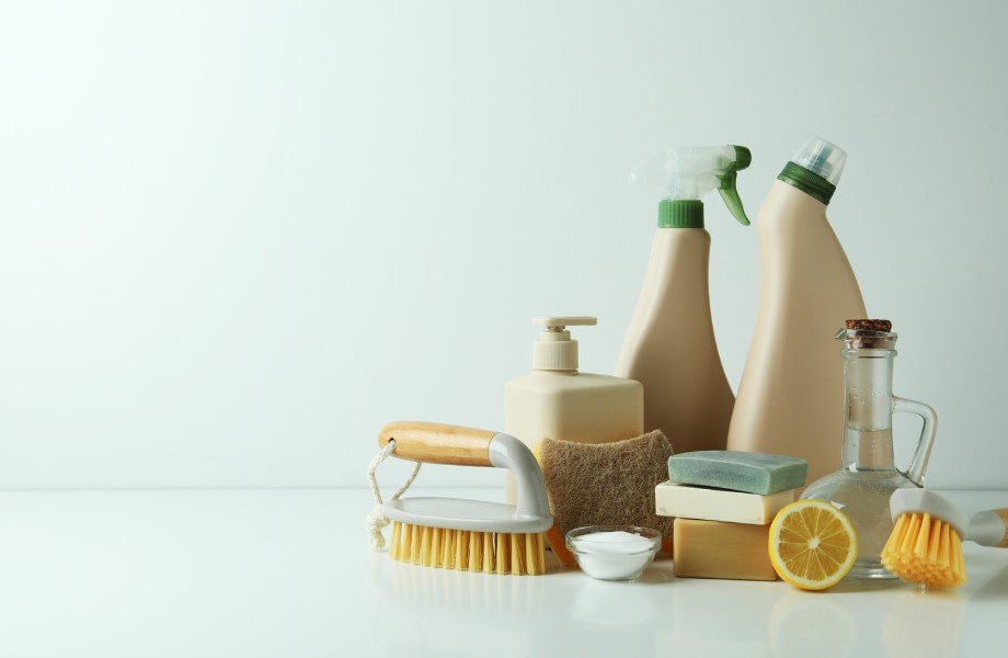 Assortment of eco-friendly cleaning products including brushes, natural soaps, vinegar, and a lemon, promoting sustainable cleaning practices.